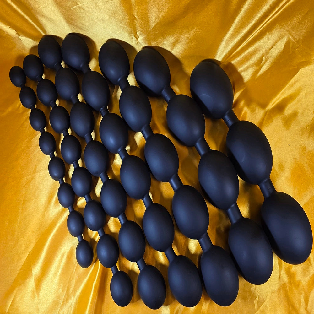 `Gruppbild som visar alla storlekar av äggformade analkulor XXL i svart färg – från Small till 4XL – på guld bakgrund. Från Chambers of Love.`
