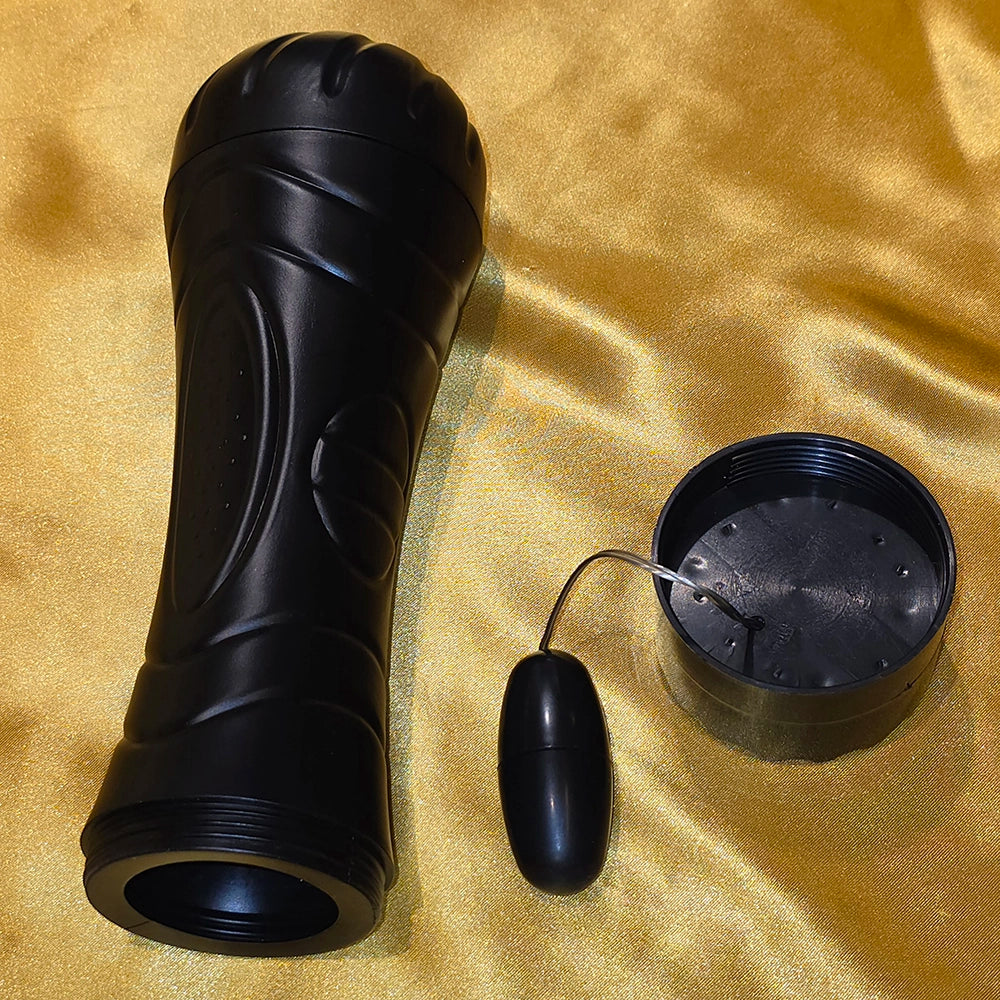 Onanikopp med Löstagbar Vibrator – Sexkopp för Män Svart, löstagbar vibrator visad separat på gyllene satin, Chambers of Love