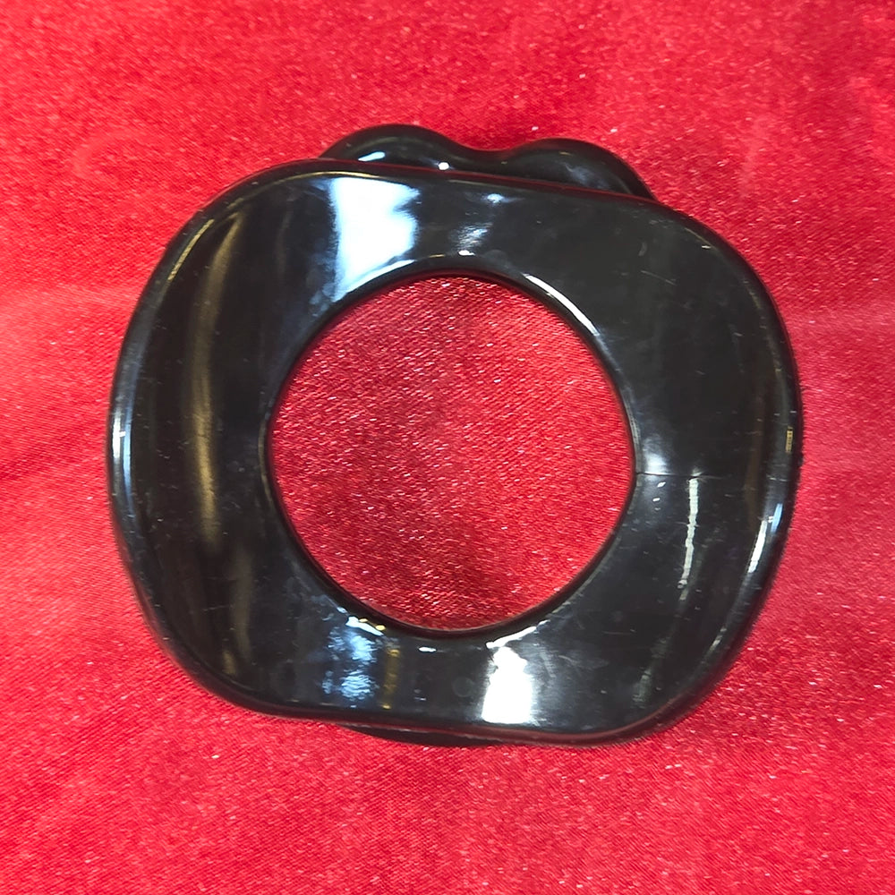 Öppen Mun Gag i svart silikon, baksida på röd glitterbakgrund. O-ring gag för BDSM och kinky lek från Chambers of Love.